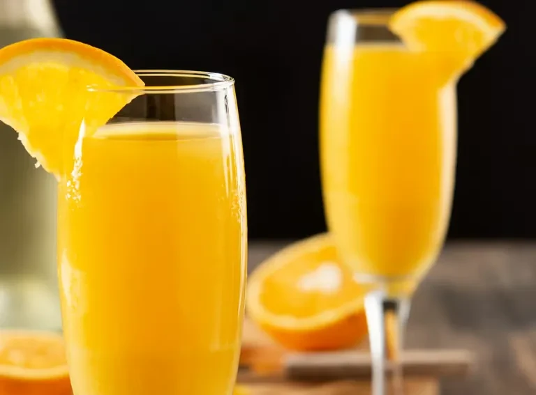 Two orange drinks with orange slices, one in focus.