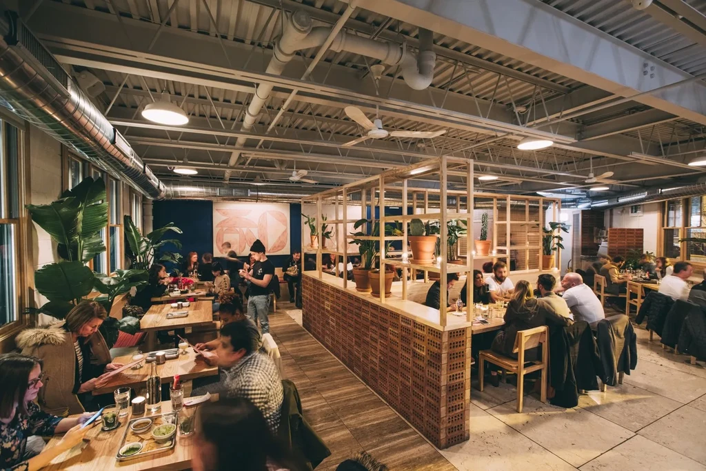 Restaurant interior with exposed beams, industrial decor, and seated patrons.