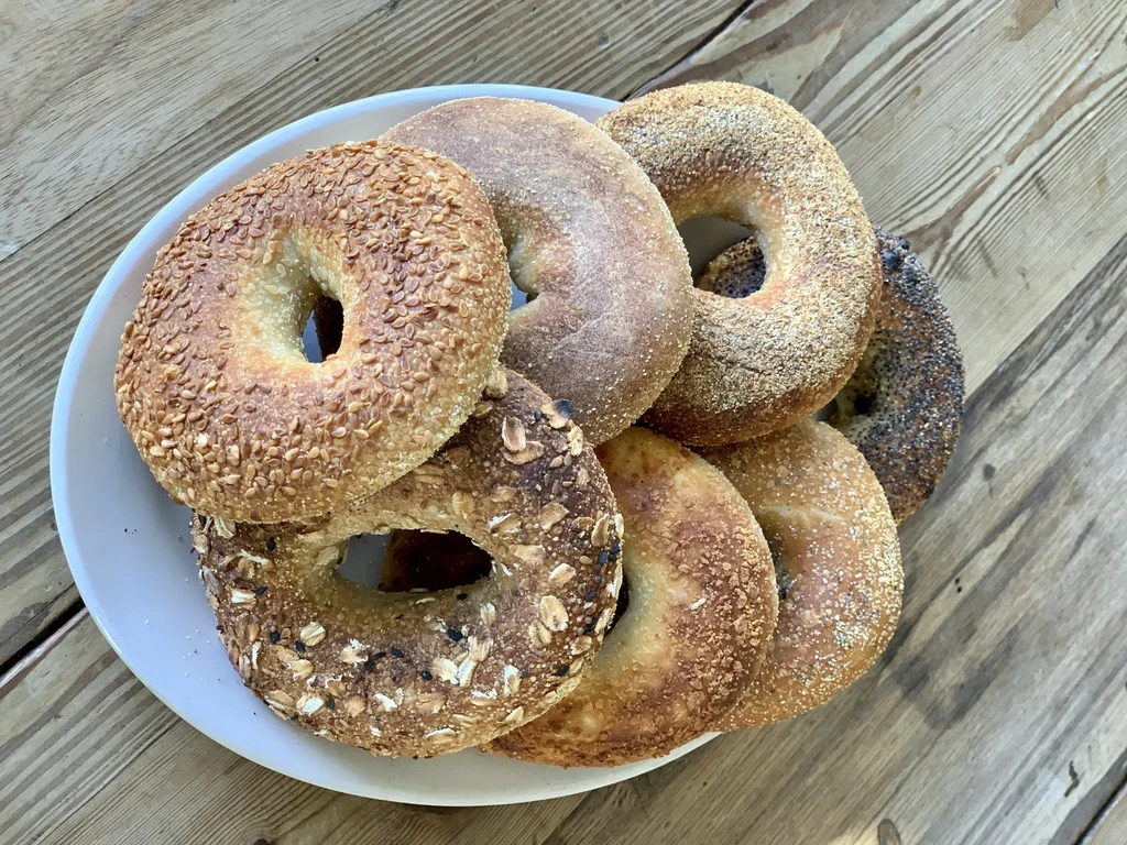 White plate filled with assorted bagels on a rustic wooden table.