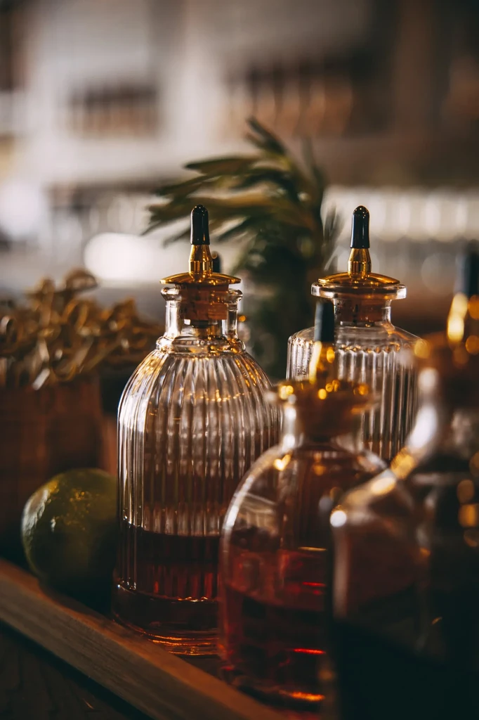 Two ribbed glass bottles with pour spouts, a lime, and rosemary.