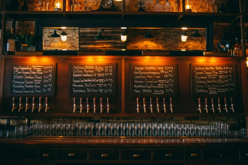 Thirty-two beer taps, chalkboards, and pint glasses at a bar.