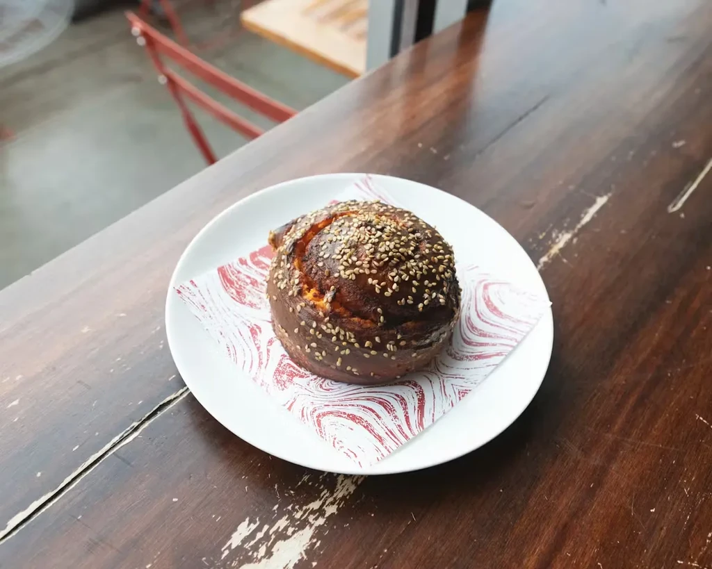 Round dark brown bun generously topped with sesame seeds.