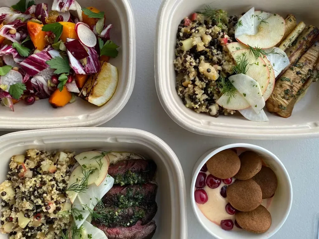 Four take-out containers filled with salads, steak, and dessert.