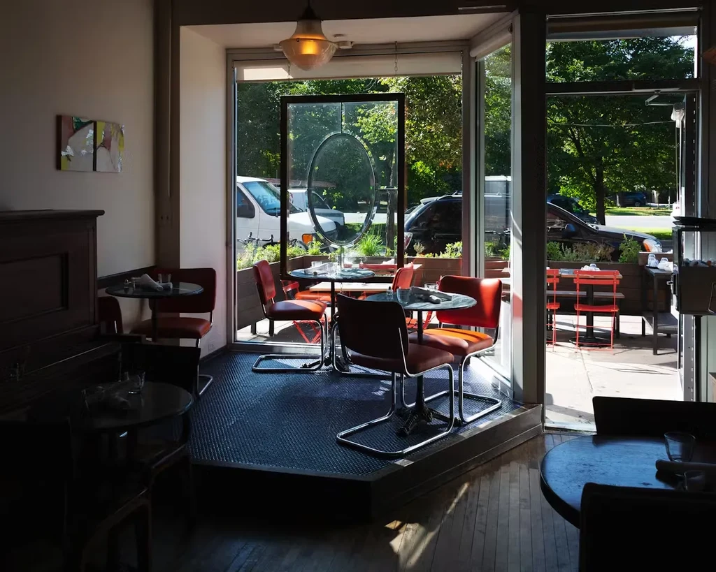 Restaurant interior with tables, chairs, and outdoor patio view.