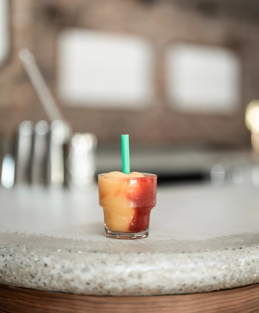 Layered frozen drink with two colors and a green straw.