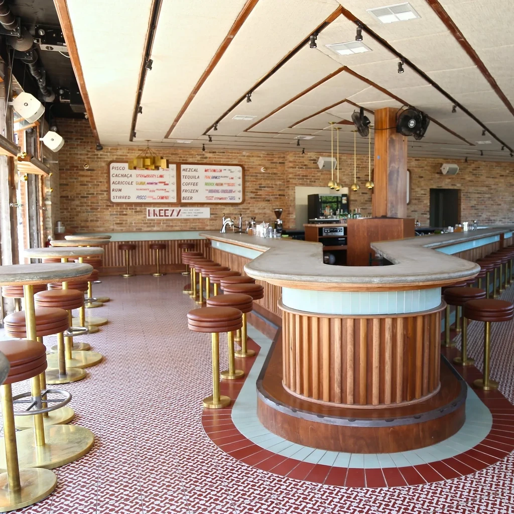 Stylish, empty bar interior with a curving counter and tiled floor.