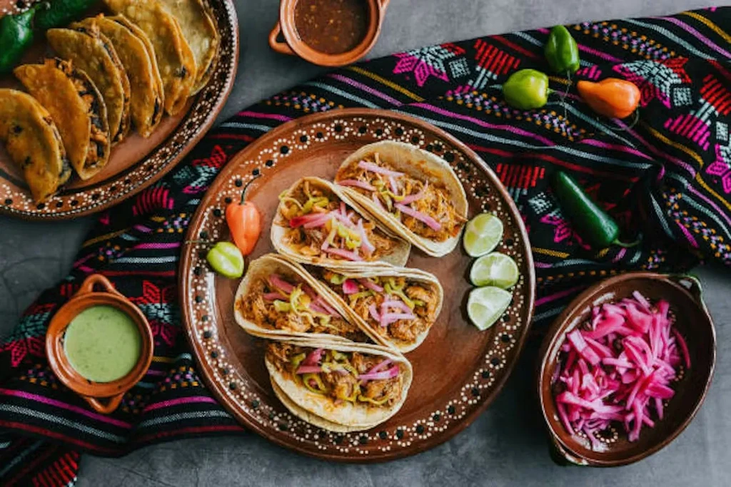 Overhead shot of two plates of Mexican tacos with various side dishes.