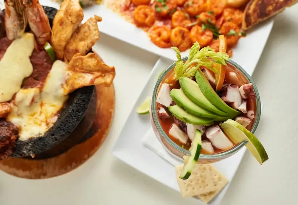 Close-up of three dishes: seafood cocktail, mixed meats, and shrimp.