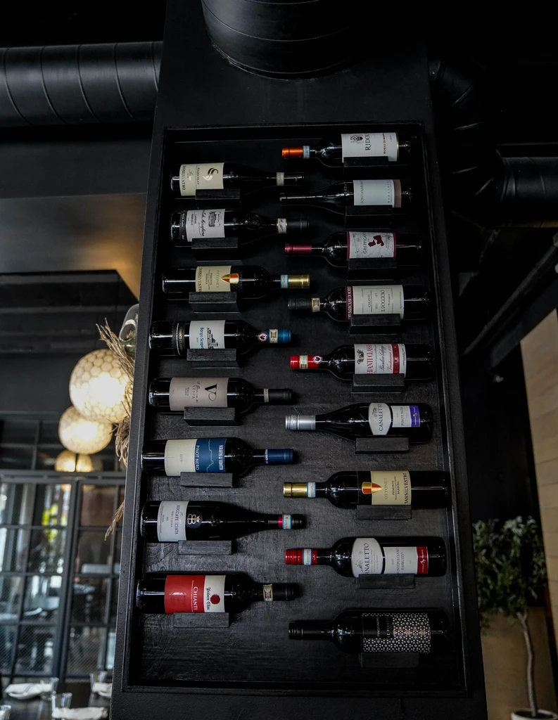 Dark, vertical wine rack filled with numerous bottles of wine.
