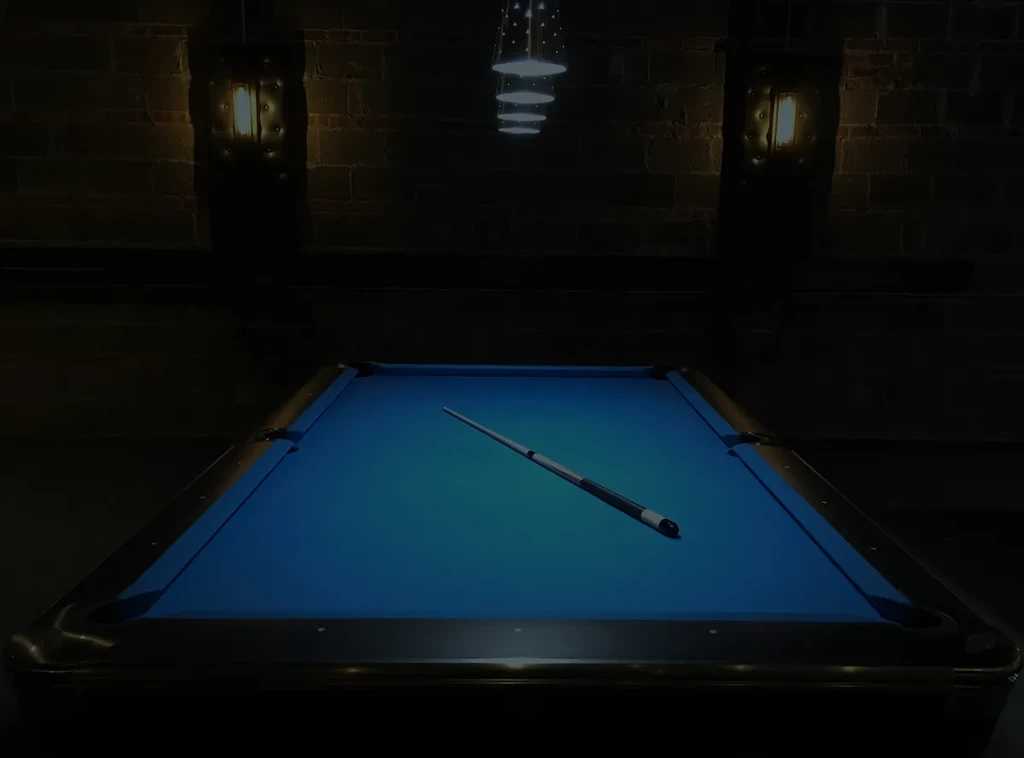 Pool table with blue felt and a cue stick under pendant lights.