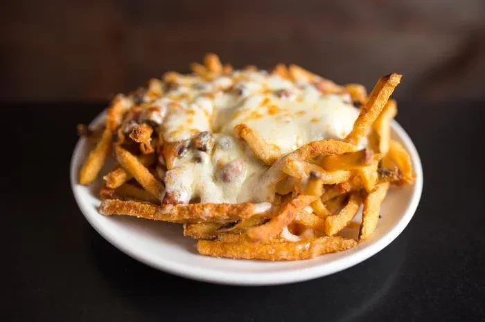 Close-up of a plate of french fries with melted white cheese.
