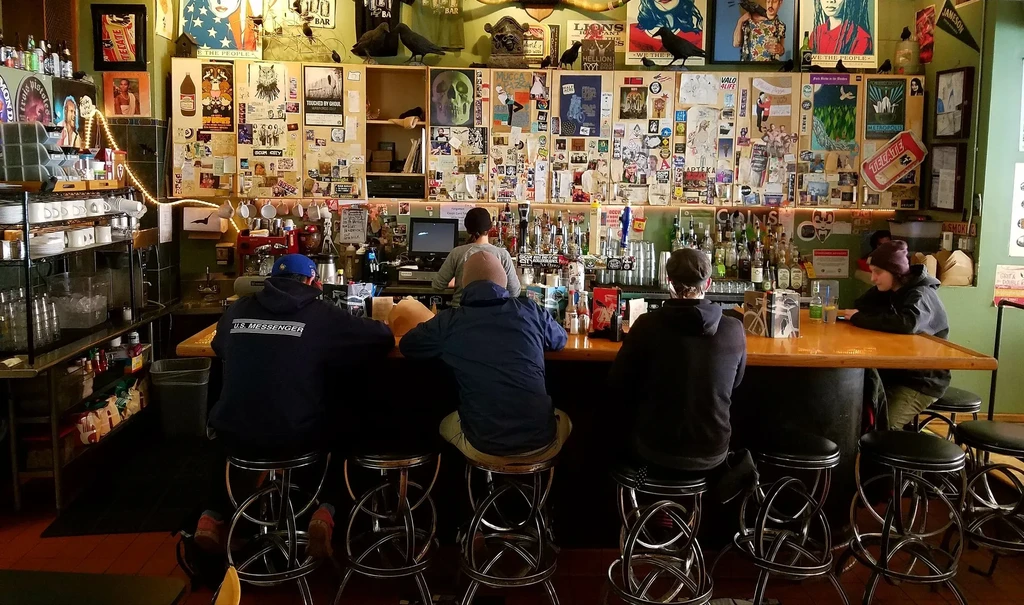 Interior view of a casual bar with patrons and a bartender.