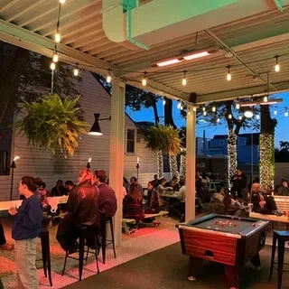 Outdoor patio at dusk with string lights, plants, and people.