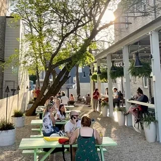 Outdoor patio with picnic tables, covered bar, and trees.