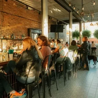 Patrons seated at a long bar counter with exposed brick walls.