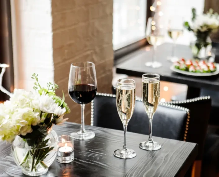 Elegantly set restaurant table with flowers, candles, wine, and champagne.