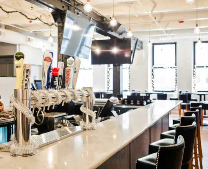 Chrome beer tap system with festive tinsel in a modern bar.