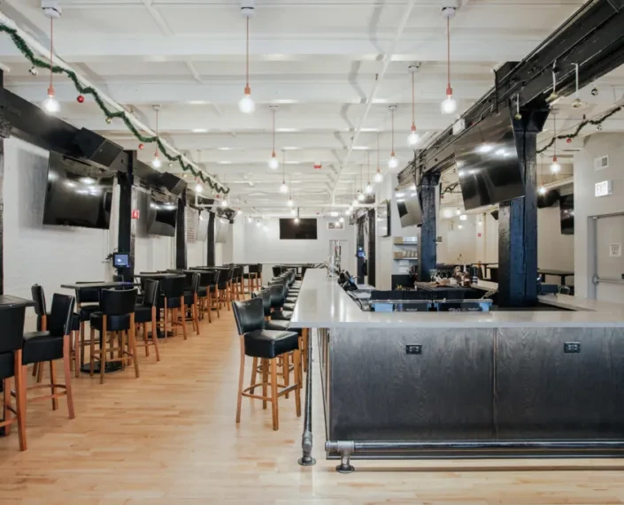 Empty bar interior with high-backed stools and holiday decorations.