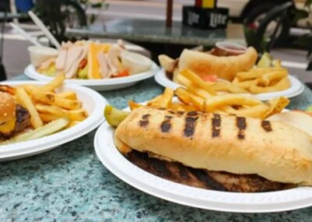 Four plates of food: grilled sandwiches, cheeseburger, salad, and fries.