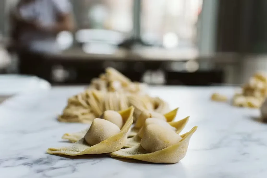 Fresh, flour-dusted tortellini and tagliatelle pasta on a light countertop.