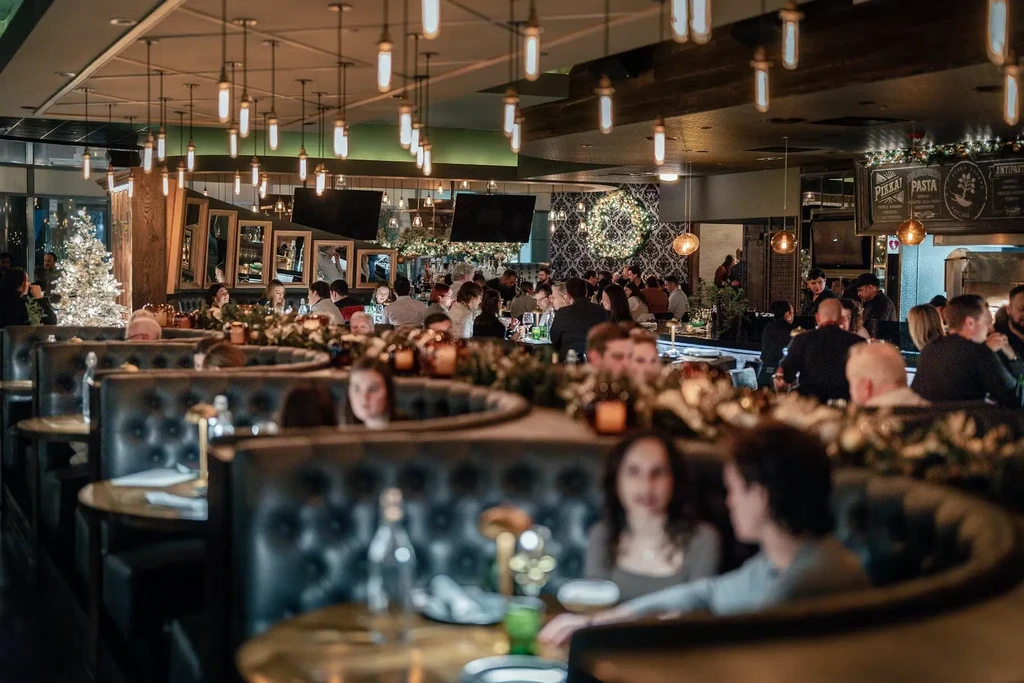 Restaurant interior with blurred patrons, pendant lights, and holiday decorations.