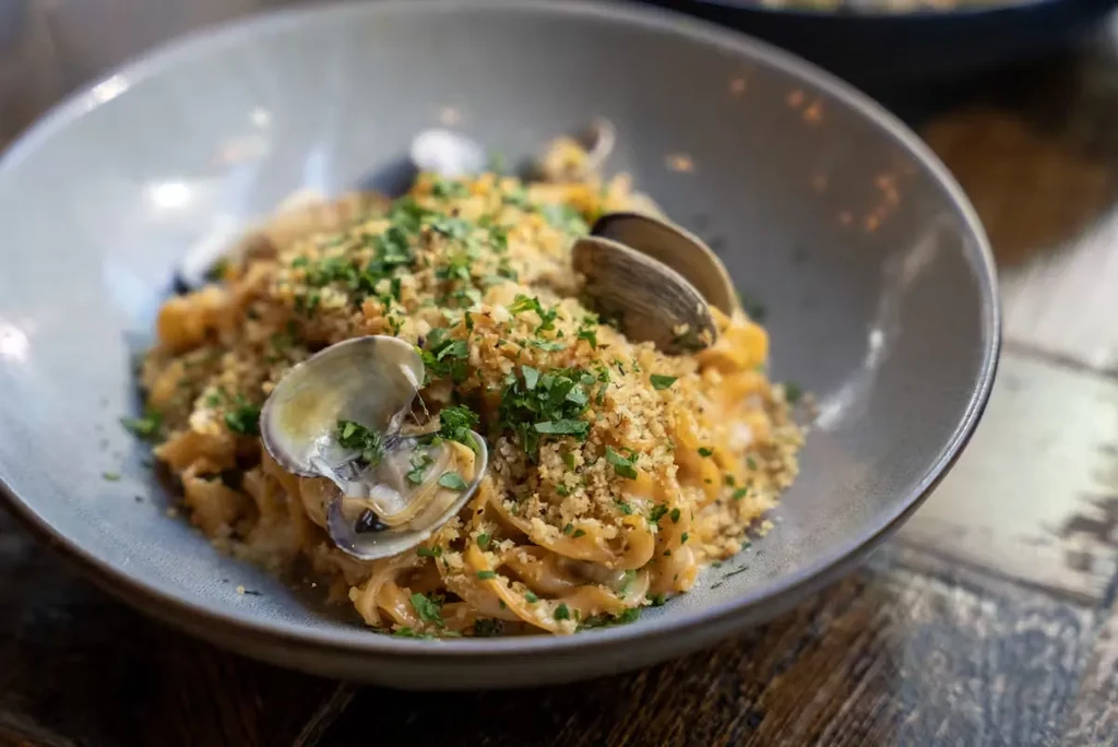 Pasta with clams, toasted breadcrumbs, and parsley in a bowl.