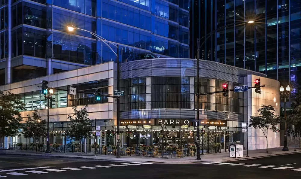 Modern building with a BARRIO restaurant on a city street at night.