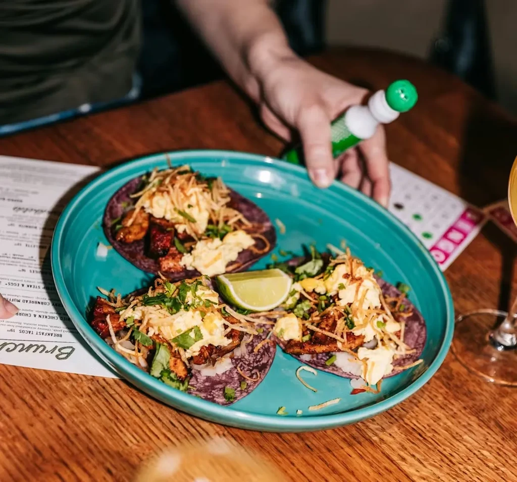 Three breakfast tacos with purple tortillas on a turquoise plate.