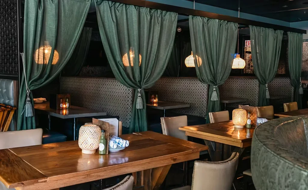 Restaurant interior with teal curtains and patterned gold booths.
