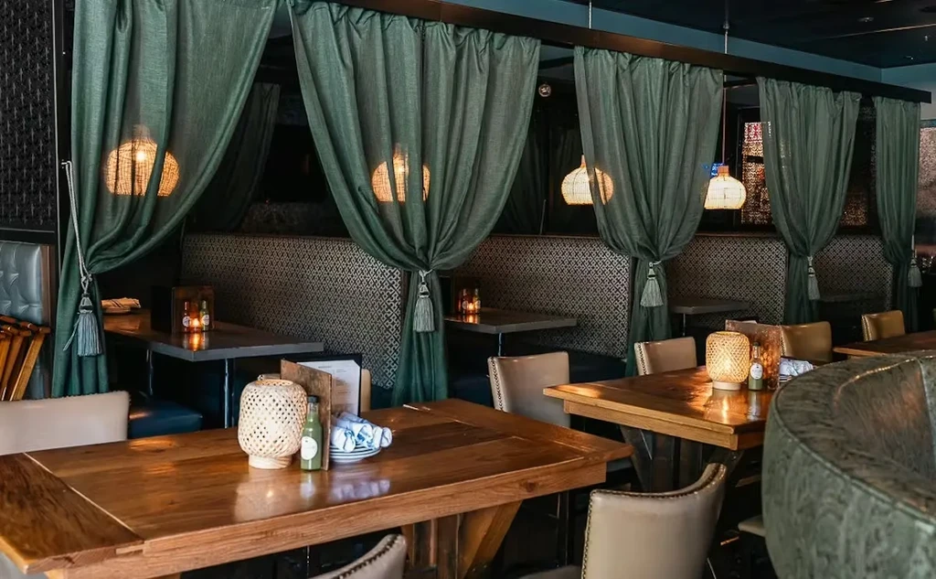 Cozy restaurant interior with wooden tables and dark green curtains.
