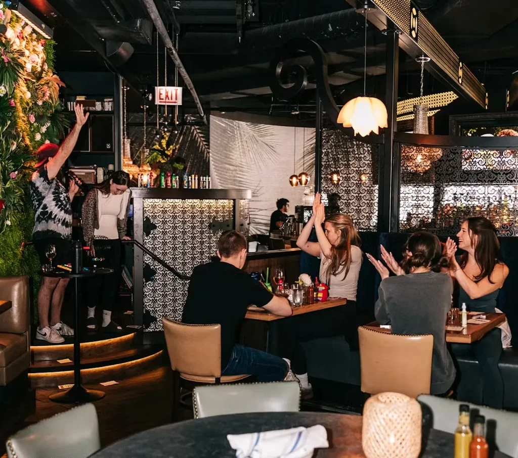 People in a dimly lit restaurant, some enjoying a performance.