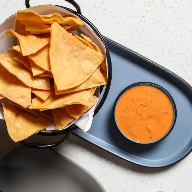Top-down view of tortilla chips and a bowl of orange dip.