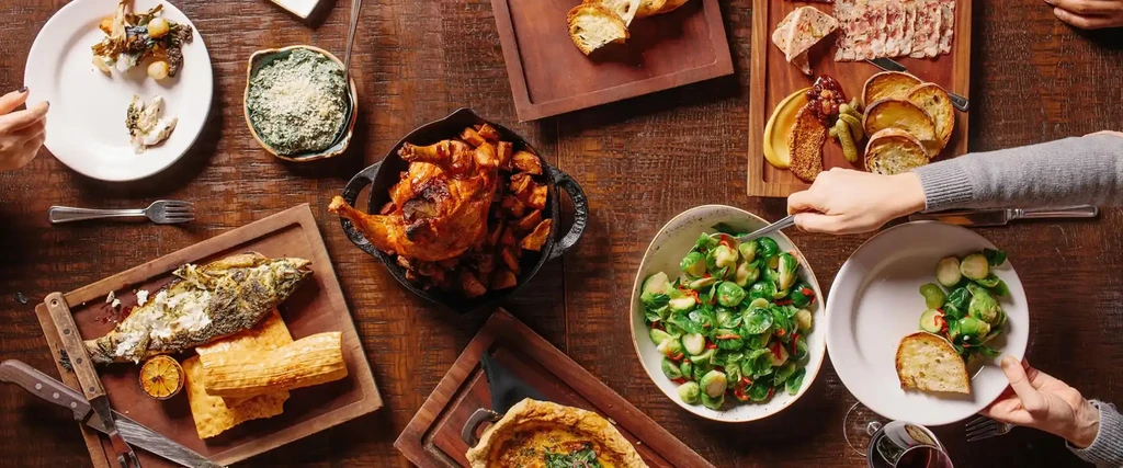 Top-down view of a wooden table laden with various food dishes.