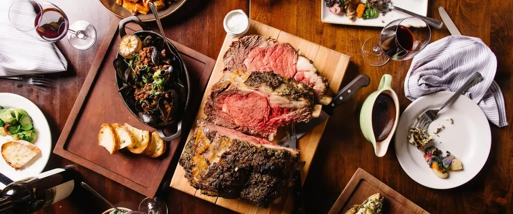 Overhead shot of a wooden dining table with a prime rib roast.