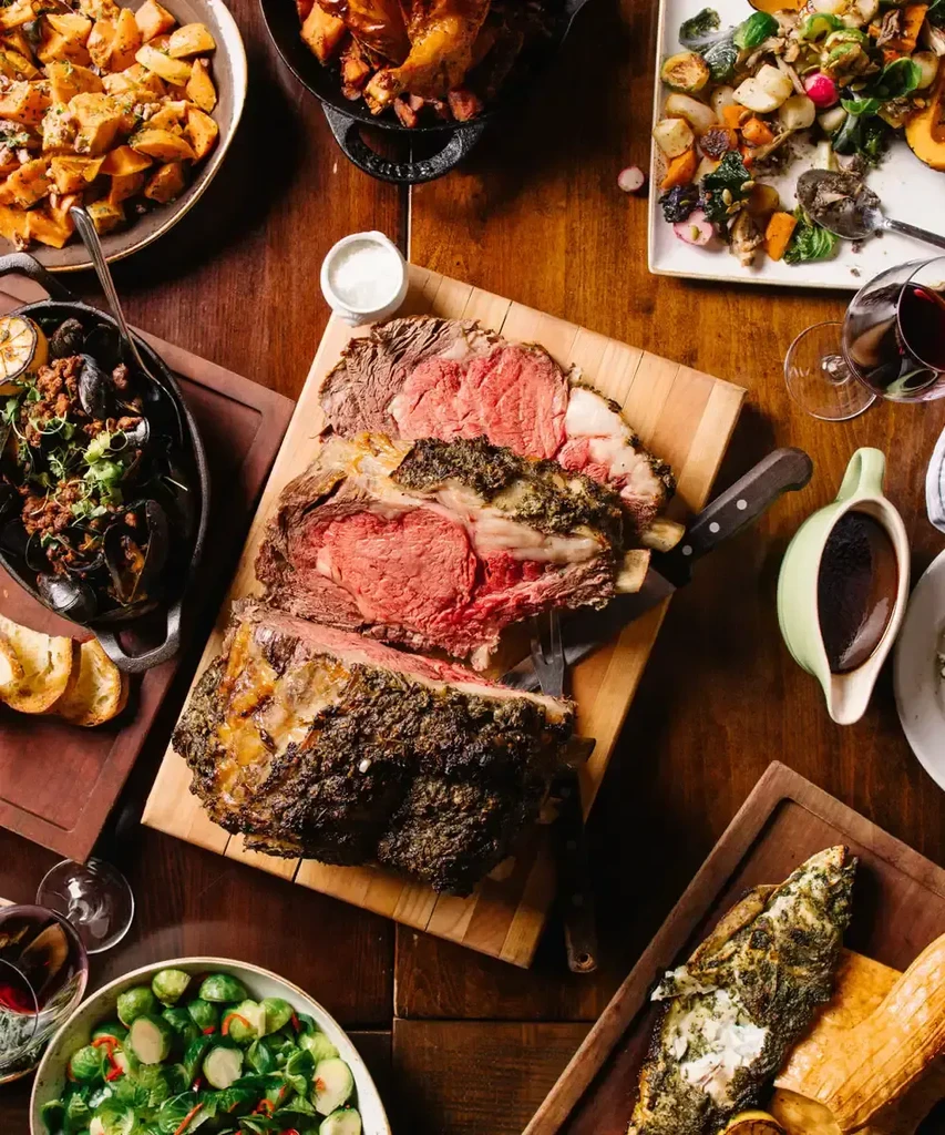 Overhead view of a prime rib dinner with various side dishes.