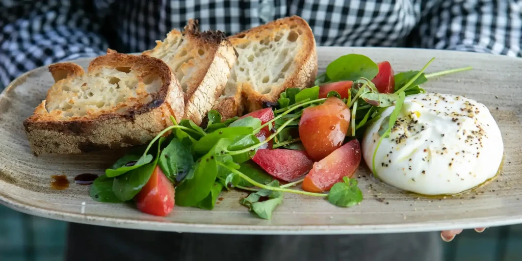 Rustic plate of toast, salad, and burrata cheese.