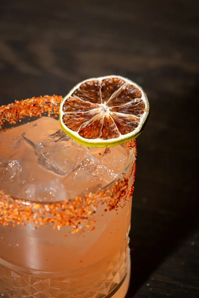 Light orange-pink drink in a textured glass with seasoned rim.