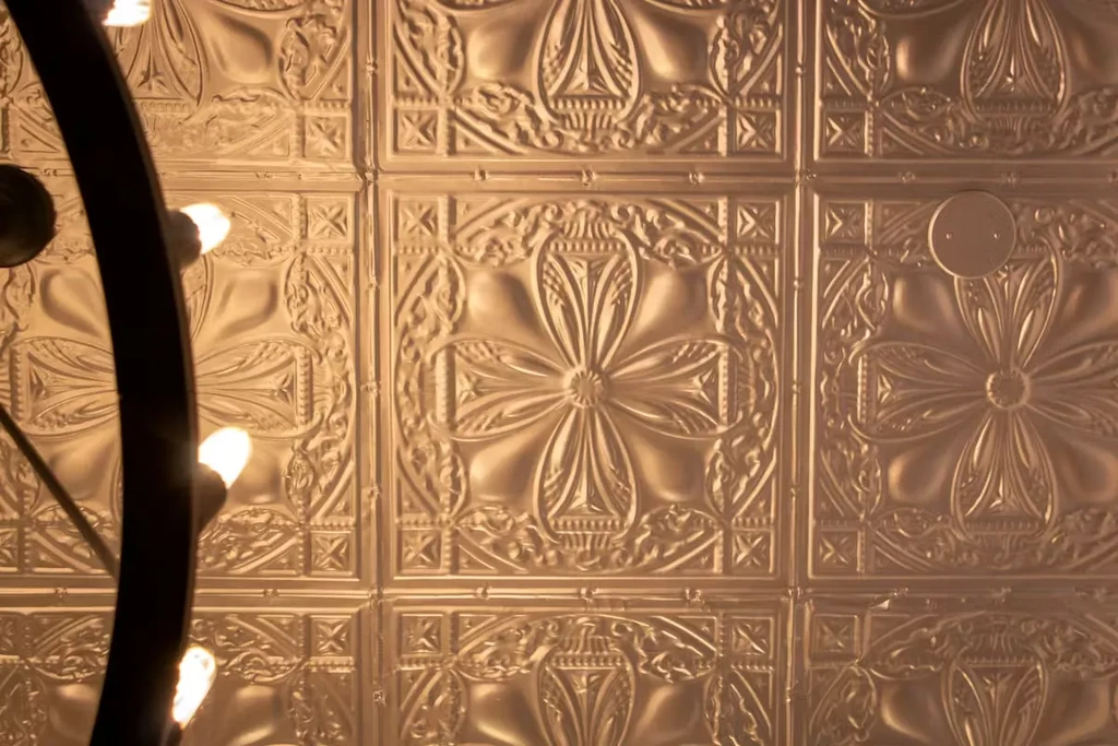 Intricate metallic ceiling with repeating patterns and a glowing light fixture.