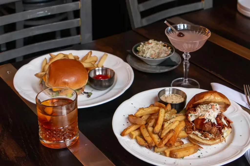 Restaurant table with two plates of food and three drinks.
