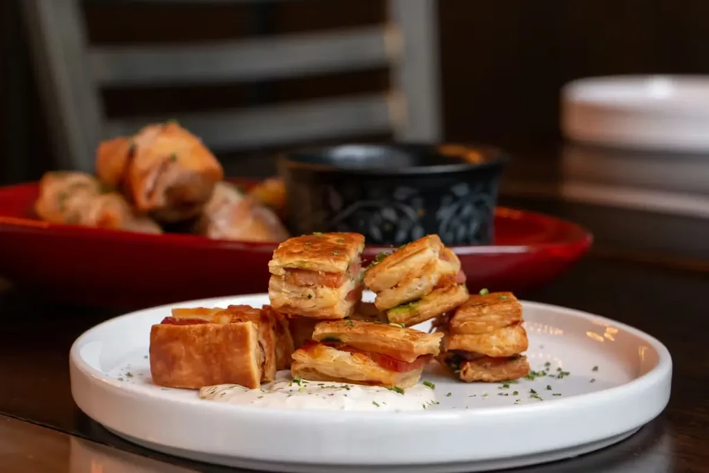 Flaky pastries with creamy sauce and green herbs on a white plate.