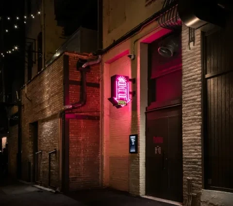 Neon arrow sign pointing to "FOOD" in a dark alley.