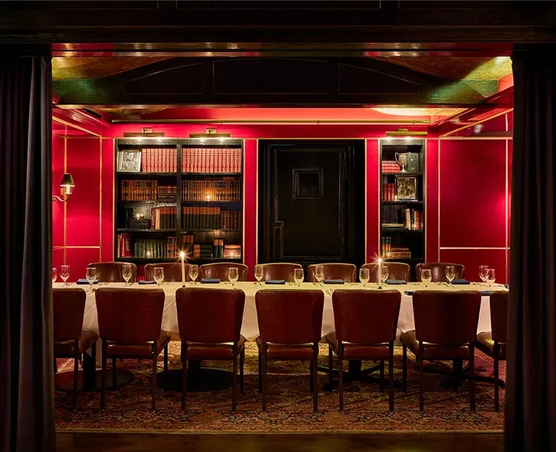 Formal dining room with red walls, bookshelves, and set table.