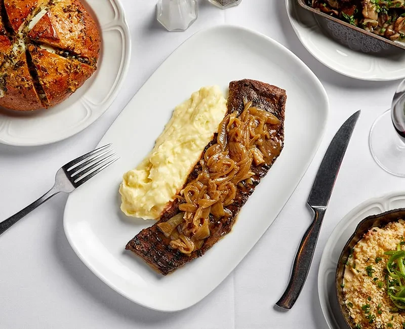 Top-down view of a steak dinner with mashed potatoes and sides.