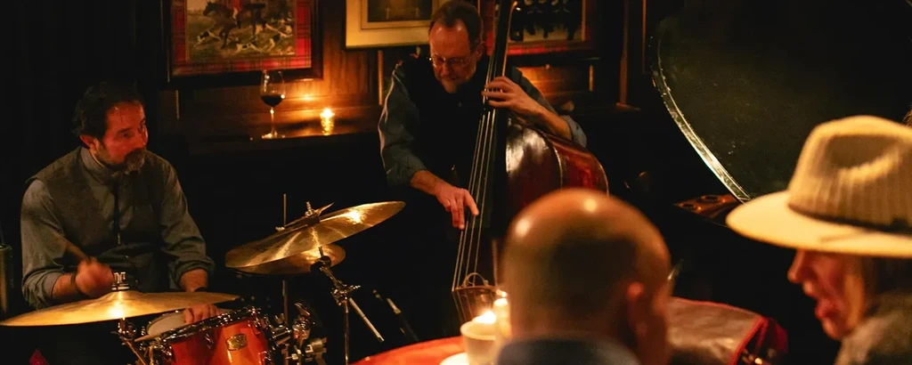 Three musicians perform live in a dimly lit bar setting.
