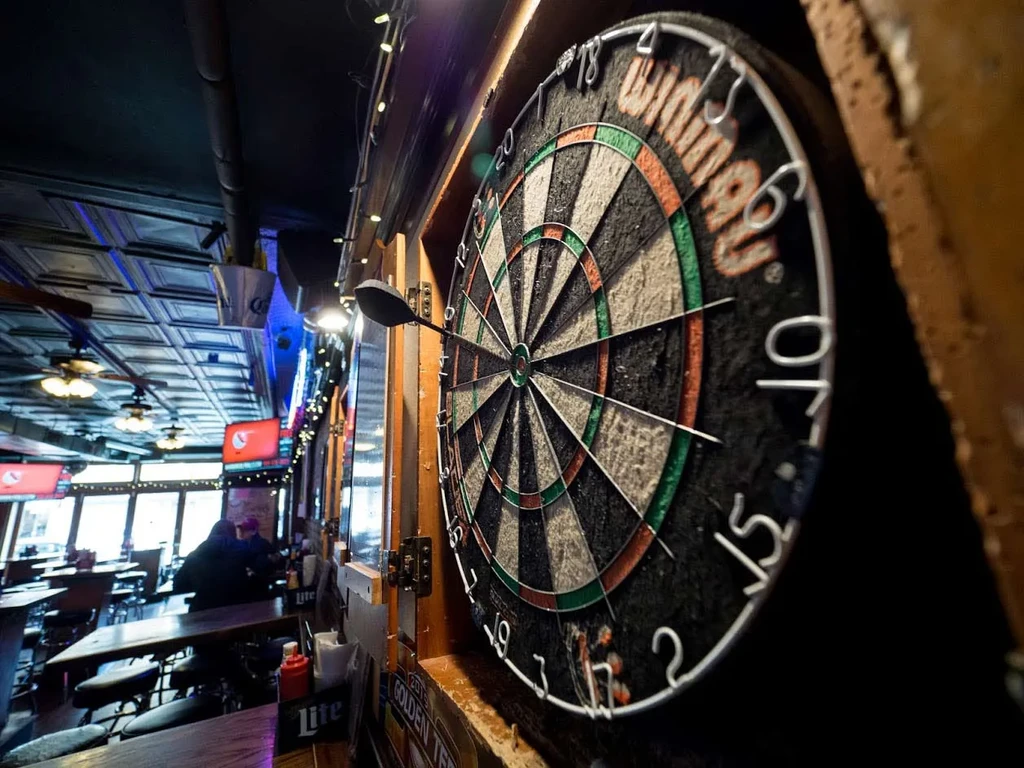A dartboard with a dart in a dimly lit bar setting.