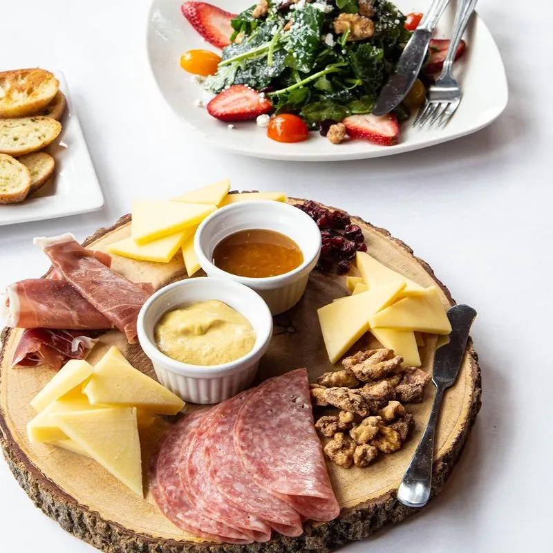 Charcuterie board with cheese, meats, condiments, dried fruit, and nuts.