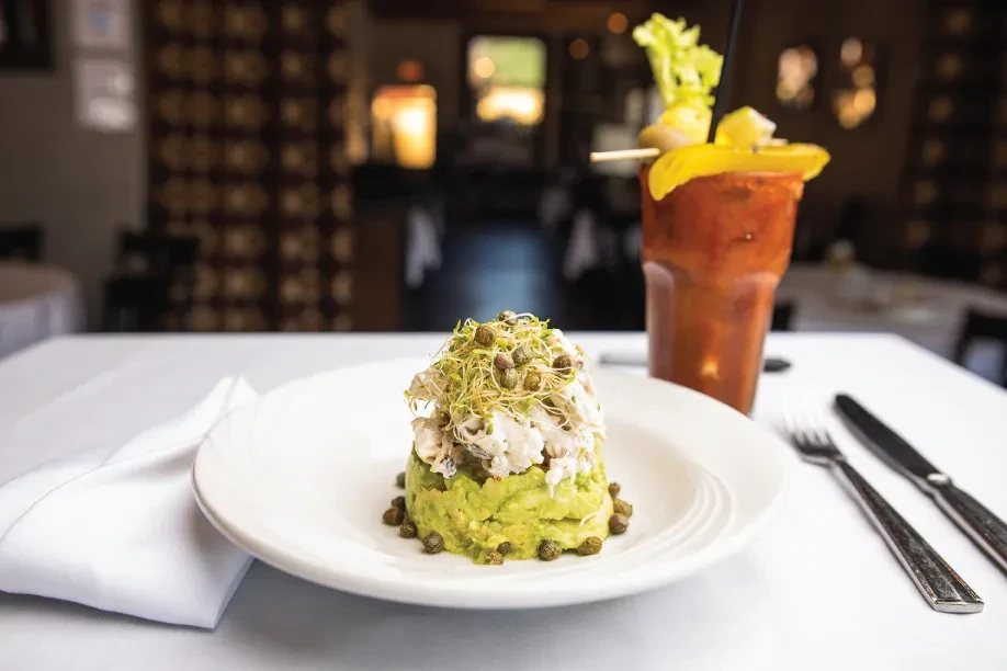 Seafood appetizer with mashed avocado and a Bloody Mary drink.
