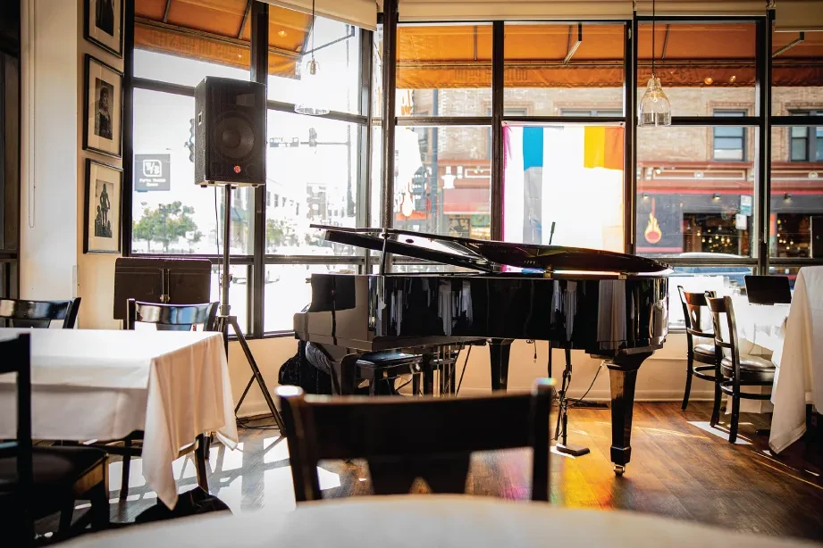 Grand piano in an elegant restaurant near large windows.