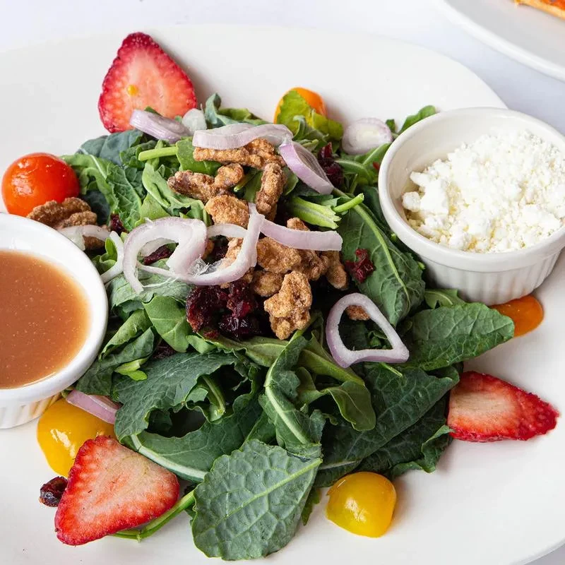 Salad with leafy greens, strawberries, nuts, cranberries, and cheese.