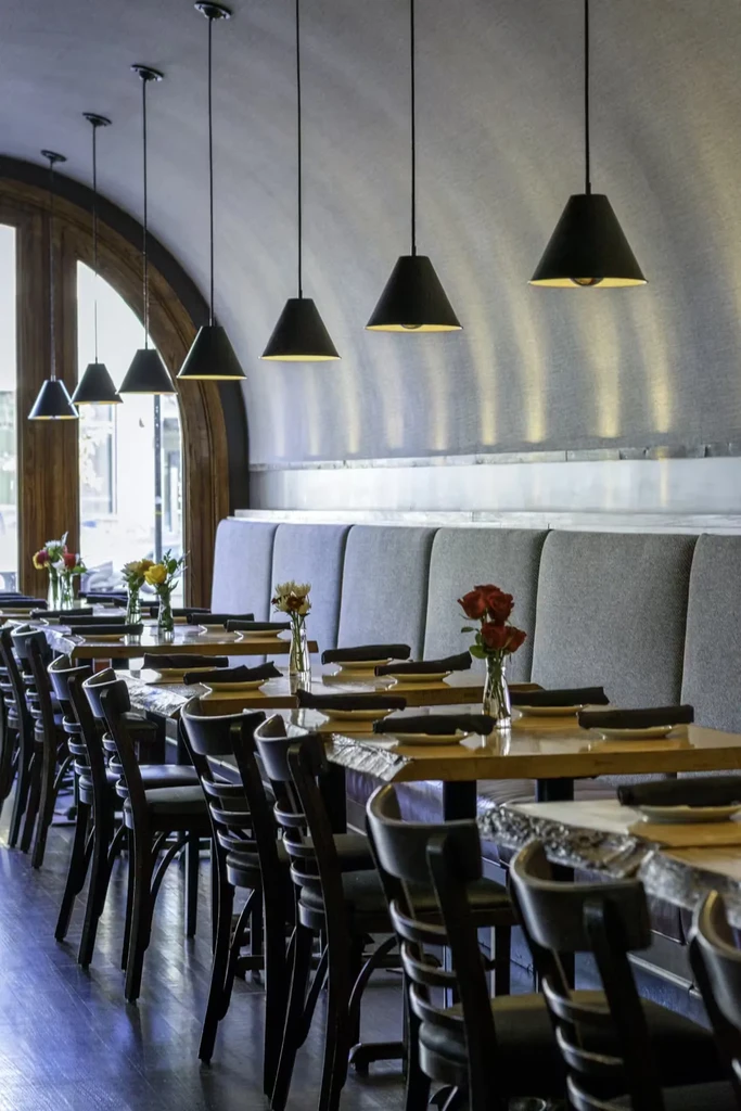 Long row of set tables in an empty restaurant dining area.